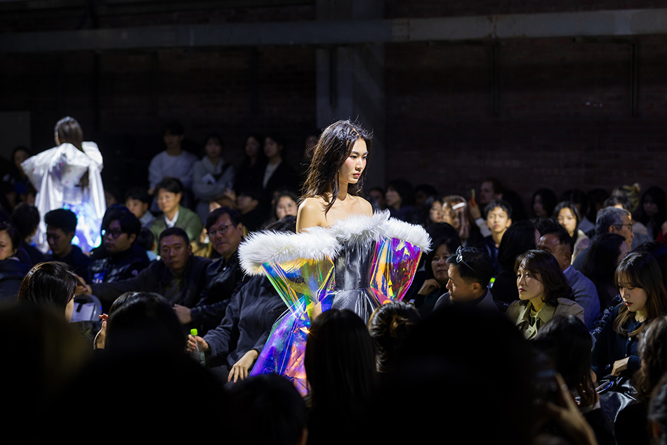 A model showcases an iridescent gown, its voluminous sleeves catching the light